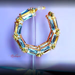 Multicolored gemstone hoop earring on a reflective surface with a blurred background