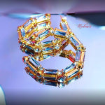 Gold and gemstone earrings on a reflective surface