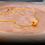 Gold necklace on a textured surface with 'Mandarin' branding.