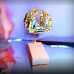 Gold and multicolored gemstone earring on a wooden stand with a blurred background