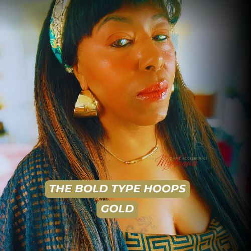 Woman wearing gold hoop earrings with text 'The Bold Type Hoops Gold' on a blurred background