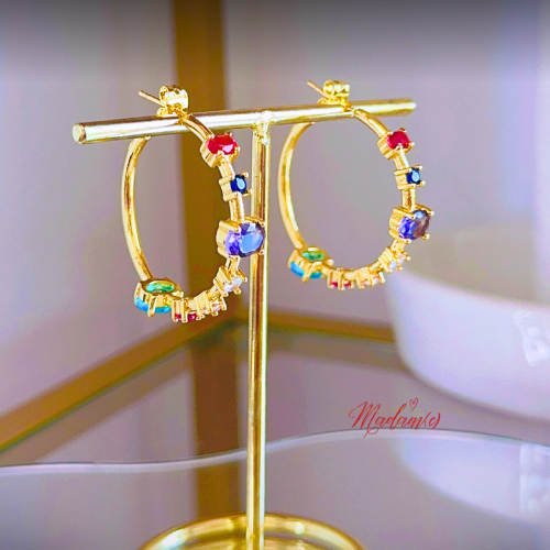 Gold hoop earrings with colorful gemstones on a gold stand, brand &