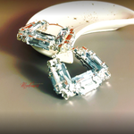 Close-up of a diamond earring on a reflective surface with 'Mestige' branding.