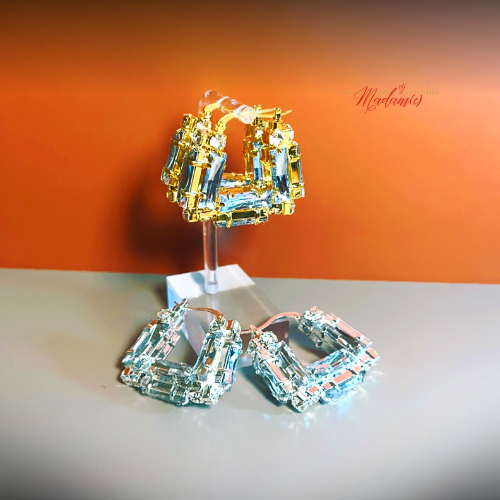 Pair of gold and silver hoop earrings on a stand against an orange background