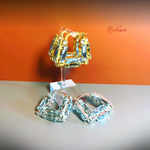 Pair of gold and silver hoop earrings on a stand against an orange background