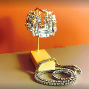 Pair of diamond earrings on a wooden stand with an orange background
