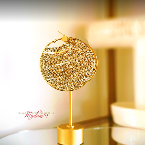 Gold hoop earring on a stand with a blurred background