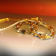 Gold bracelet with gemstones on a reflective surface