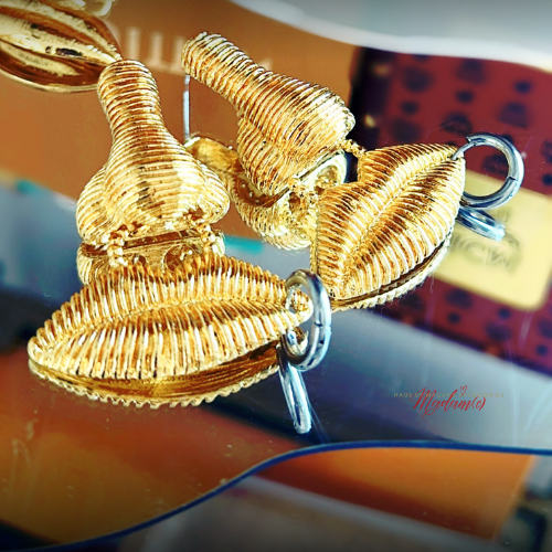 Gold earrings on a reflective surface with a blurred background