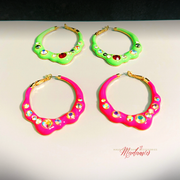 Four colorful hoop earrings with gemstone-like embellishments on a light background.