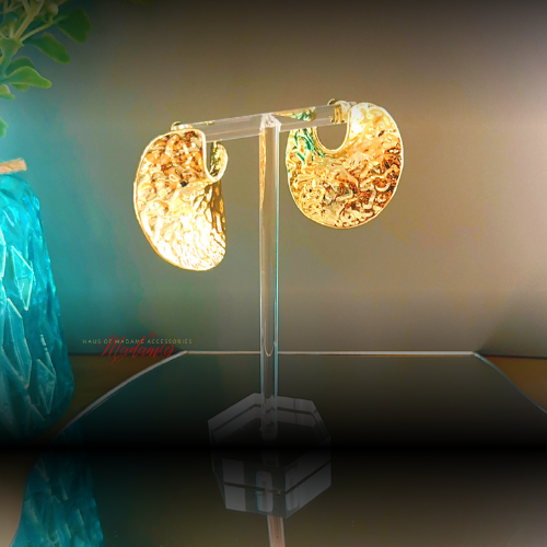 Gold hoop earrings on a clear stand with a blurred background