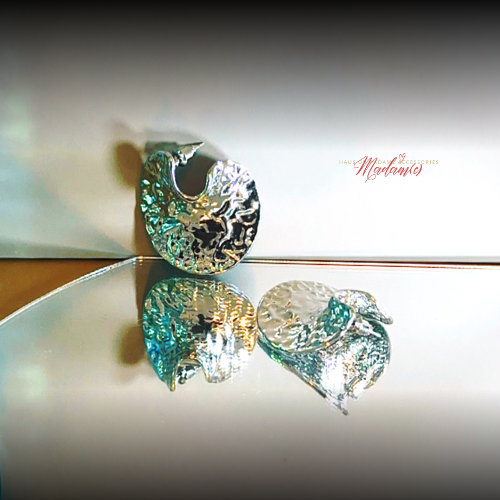 Silver earrings with a reflective surface on a light background