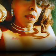 Close-up of a woman wearing gold earrings and a diamond necklace with a blurred background.