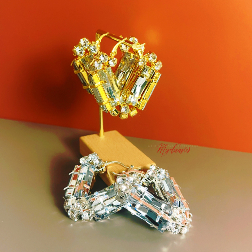 Gold and silver earrings on a stand with an orange background