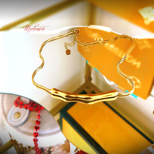Gold necklace on a reflective surface with a blurred background