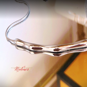 Silver necklace on a reflective surface with 'Mysteries' branding.