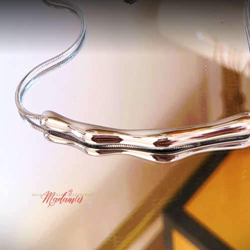 Silver necklace on a reflective surface with 'Mysteries' branding.